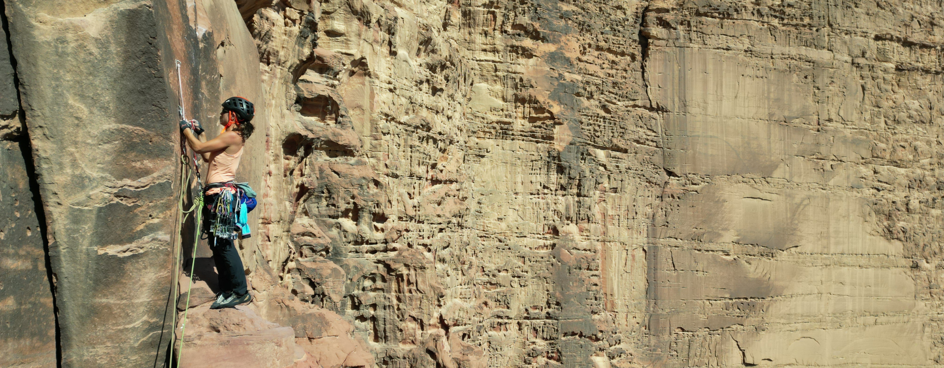 Mujer escalando en una inmensa pared de roca