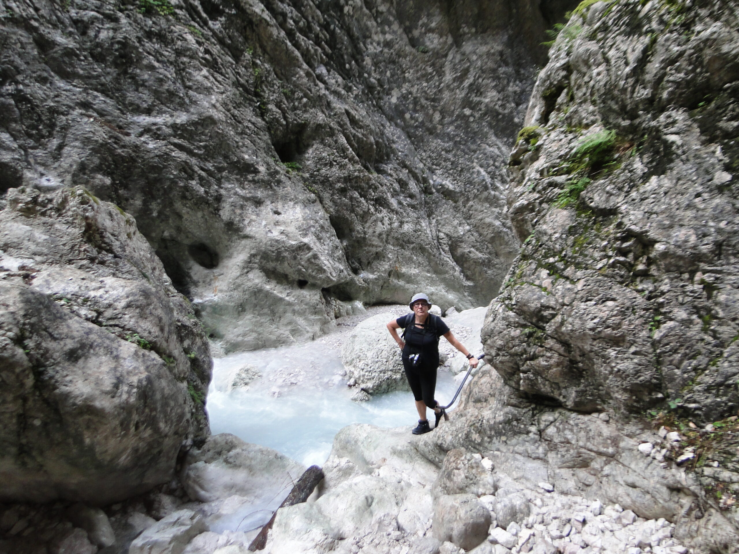 Magdalena Humbert Pons se encuentra en la Val Òten, cerca de Cortina d´Ampezzo, al norte de Italia. Es un cerrado barranco con escarpadas laderas de piedra y un río de aguas bravas al fondo. Ella aparece de pie muy cerca de agua, con ropa oscura y sombrero, agarrada a una especie de cable.