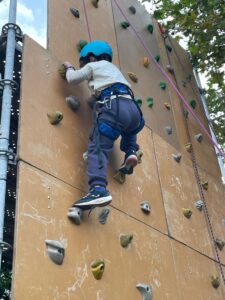 Un participante de unos 5 años de edad está a punto de hacer top ascendiendo por la pared del rocódromo en top rope. 